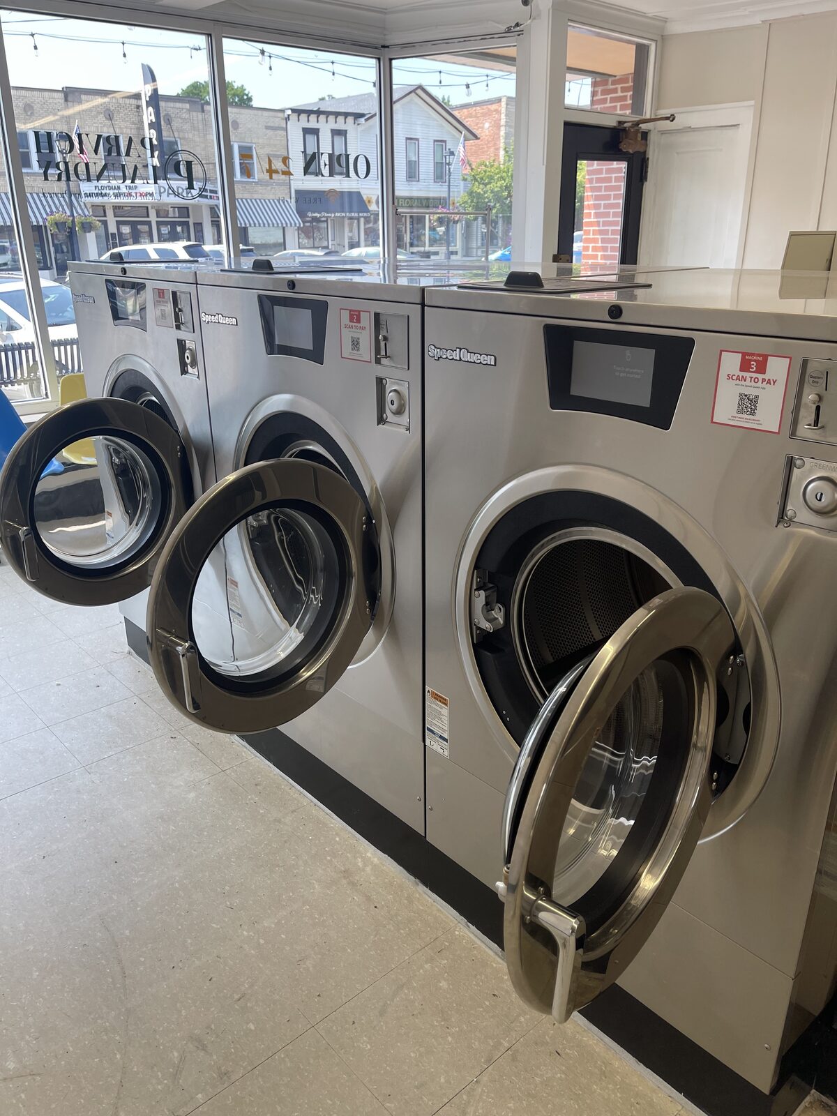 Speed Queen 60 lb front-load washers by the storefront windows at Parvich Laundry